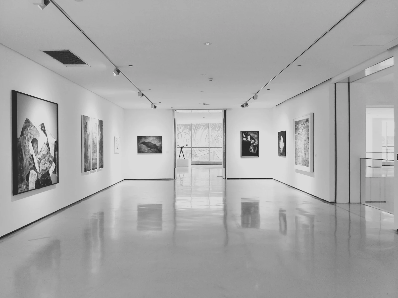 assorted paintings on white painted wall. Photograph accompanying Velaharra’s cross-border creative projects guide.