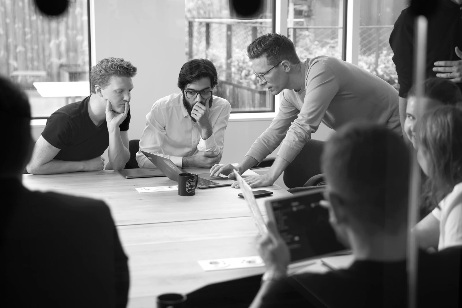 a group of people sitting around a wooden table. Photograph accompanying Velaharra’s artist collaboration brief guide.